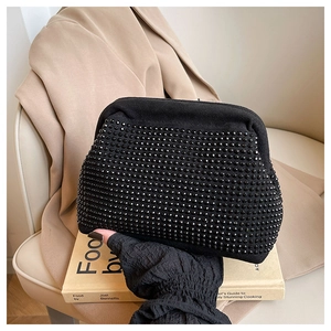 Detail of black suede clutch bag featuring 3D studded texture and sleek metal clasp