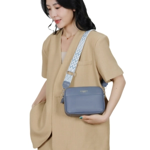 Gray-blue leather camera bag with a wide geometric patterned strap shown on a model