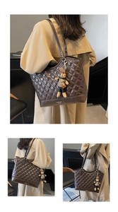 Detail view of large quilted brown tote bag with stylish bunny charm and soft leather texture