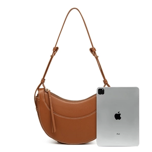 Brown half-moon saddle bag in textured leather shown next to an iPad for size reference