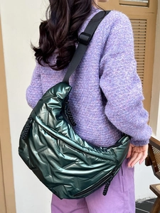 Quilted metallic dark green tote bag with adjustable strap worn by model in winter style