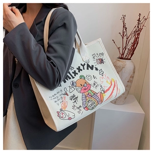 Detail of white canvas tote bag featuring artistic cartoon bear and graffiti print