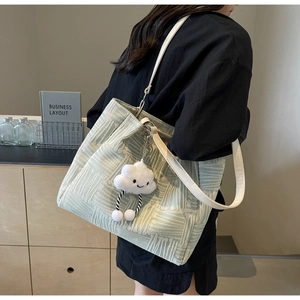 Detalle del bolso tote tejido verde con correa de cuero blanco y colgante de nube