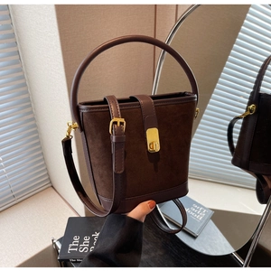 Detail of vintage brown bucket bag showing suede texture, gold buckle, and leather handle