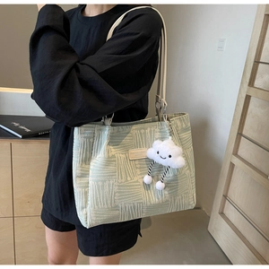 Primer plano de bolso tote verde claro con textura, etiqueta de cuero y colgante suave