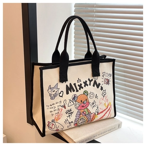 Detail of canvas tote bag featuring stylish graffiti prints and black fabric handles