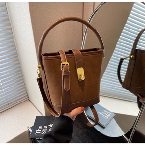 Detail of dark brown suede bucket bag with leather trim and gold twist lock closure
