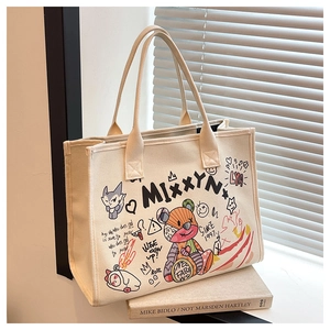 Detailed close-up of cream canvas tote bag with vibrant bear and cat graffiti prints