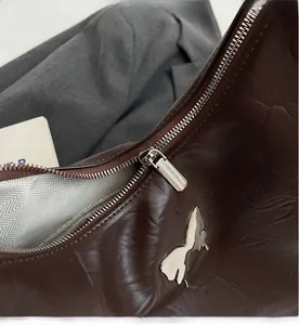 Macro shot of dark brown glossy leather texture with silver bow and smooth zipper detail