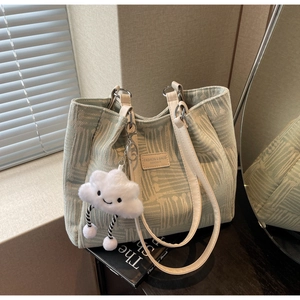 Detalle de bolso tote tejido verde menta con parche de cuero y amuleto de nube de peluche