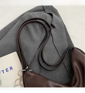 Detail showing the brown leather handbag with a chain strap over a grey suit blazer