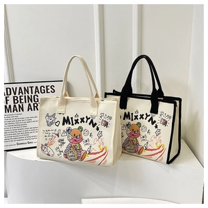 Detail view of canvas tote bags with modern artistic graffiti and wide handles on display