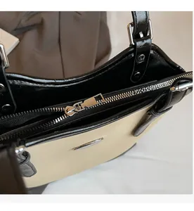Detail of smooth metal zipper and round decorative plate on contrast tote bag