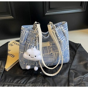 Detalle del bolso tote azul texturizado con asas de cuero y un colgante de nube