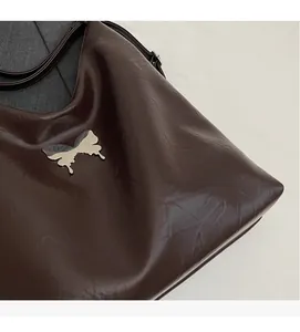 Detail of dark brown tote bag showing supple PU leather texture and silver butterfly buckle