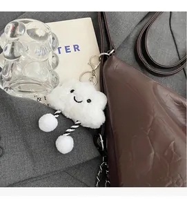 Close-up of white plush cloud charm with striped legs on a brown tote bag