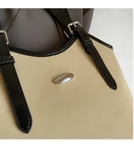 Detail of adjustable shoulder strap and silver brand logo on the cream tote bag