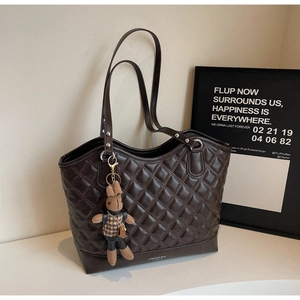 Detail der dunkelbraunen Stepptasche mit Kaninchenanhänger und Fashion Bag Logo-Schrift