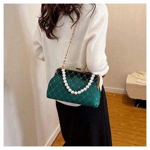 Close-up of dark green velvet pearl handbag with gold chain and quilted texture details