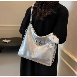 Detail of silver crinkled tote bag with metal butterfly and plush cloud charms