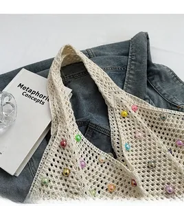 Detail of woven beige tote bag with colorful pearls on denim and book backdrop