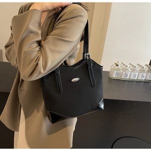 Detail of minimalist black nylon shoulder bag with leather trim and metal logo