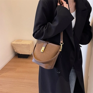Brown bucket bag in mixed leather finish worn by a model in a minimalist setting