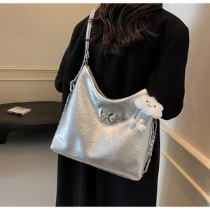 Detail of silver metallic wrinkled bag featuring a butterfly charm and cloud pendant