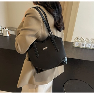 Detail of black tote bag with matte and patent leather texture and silver buckle