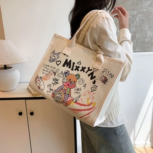 Minimalist cream canvas tote bag with colorful graffiti art shown on model's shoulder