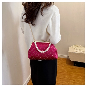 Detail of fuchsia velvet shell bag with quilted texture, pearl handle and gold chain strap