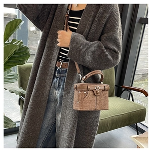 Brown vintage crossbody bag with denim pocket details and metal studs in a casual setting