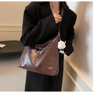 Close-up of brown textured tote bag with butterfly detail and plush cloud charm