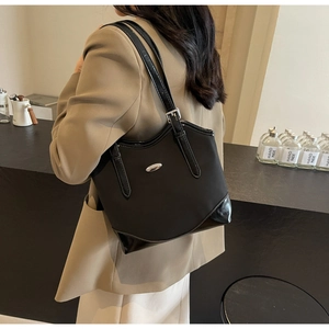 Detail of black tote bag featuring nylon leather patchwork and silver metal logo plate