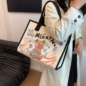 Canvas graffiti tote bag with bear patches and black straps shown on shoulder