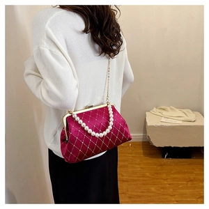 Detail of burgundy velvet quilted handbag with pearl handle and gold chain strap
