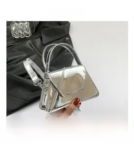 Detailed shot of metallic silver patent leather handbag with adjustable strap and handle
