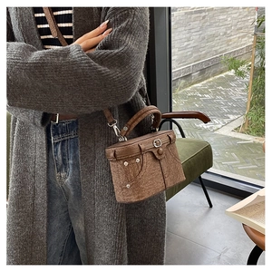 Detailed view of brown canvas crossbody bag with vintage denim pocket design and rivets