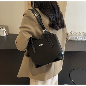 Detail of black nylon and patent leather shoulder bag with silver oval metal logo