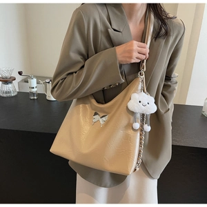 Detail of beige wrinkled leather shoulder bag with silver bow and plush cloud charm