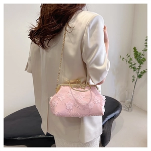Close-up of pink embroidered evening bag with 3D floral details and golden chain