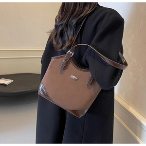 Detail view of brown matte leather underarm bag with contrast trim and silver hardware