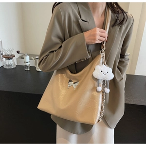 Detail of apricot PU leather shoulder bag with silver butterfly charm and chain strap