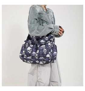Detail of blue quilted canvas bag featuring skull and rose prints with a flap pocket