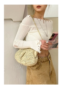 Detail of a beige woven straw cloud bag with elegant gold chain strap for beach vacations