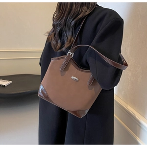 Close-up of a brown patchwork tote bag with a silver buckle and glossy leather details