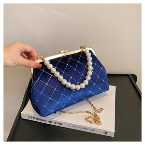 Detail of navy blue satin shell bag featuring diamond pattern, pearls and gold chain