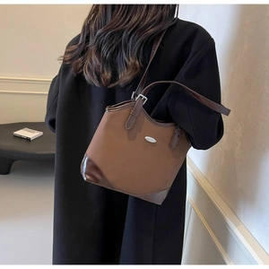 Close-up of vintage brown patchwork shoulder bag with sleek metallic logo detail