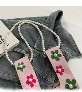 Detail of pink knitted strap with flower jacquard and pearls on a stylish shoulder bag