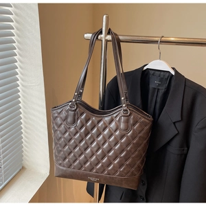 Detail der dunkelbraunen Stepptasche mit dünnen Schultergurten und Fashion-Logo